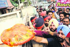 Members of the Youth Akali Dal place an onion gift pack at the gate of the Union Minister Manish Tewari’s house in Ludhiana on Wednesday