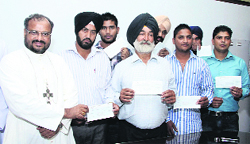 Punjabi youths deported from the UK get financial aid from the Navjeevan Charitable Society of the Jalandhar Diocese on Thursday. Photo: Sarabjit Singh