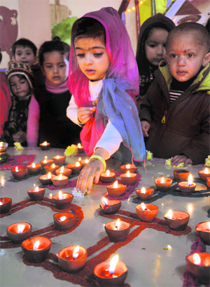 Children light earthen lamps ahead of Diwali in Shimla on Friday.