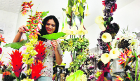 A woman arranges flowers at a shop.