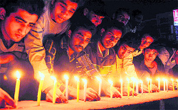 Members of the National Students Union of India (NSUI) light candles in the memory of the natural disaster victims at Clock Tower in Dehradun on Saturday