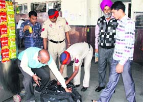 Policemen check bags of passengers at the railway station in Jalandhar on Saturday