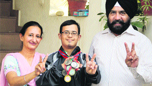 Special athlete Ishwinder Singh shows his medals along with his parents in Jalandhar on Monday. 