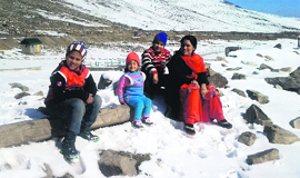 A family enjoys the sunny weather after the seasons first snowfall in Pir Ki Gali, Poonch district, on Saturday.