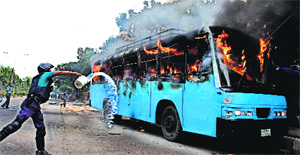 A policeman tries to douse the fire on a bus set alight during a protest ahead of a three-day strike, in Dhaka on Sunday.  