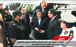 An image grab taken from Egyptian state TV shows ousted Egyptian president Mohamed Morsi (C) arriving at a court in Cairo on Monday. 