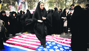A woman steps on a US flag outside the former US embassy in Tehran on Monday during a protest to mark the 34th anniversary of the 1979 US embassy takeover. 