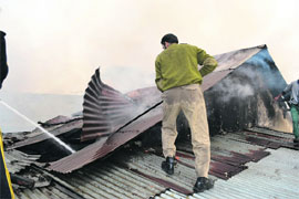 A firefighter extinguishes fire at a confectionery manufacturing unit in Anantnag on Wednesday. 