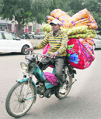 With the onset of winter, a man carries quilts on his bicycle. 