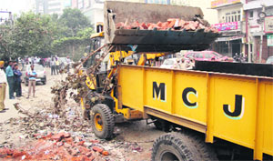The Municipal Corporation staff raze an encroachment near the busy BMC flyover in Jalandhar on Thursday.
