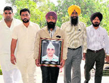 Jaspal Singh carries a picture of his son, a kabbadi player from Bhawanigarh, who was electrocuted in Bathinda last month, on his way to meet the Deputy Commissioner and senior police functionaries in Bathinda on Friday.