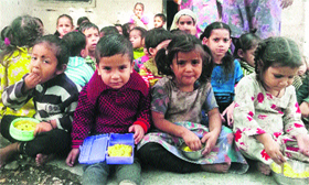 Kids enjoy a meal at an anganwadi in Talwara on Friday.