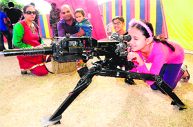A girl peeps through the scope of a gun on display at the Army exhibition in Mohali.