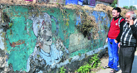 Pedestrians look at a painting on the Heritage Point in Jammu on Saturday.