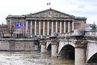 The French flag flies atop the National Assembly building in Paris.