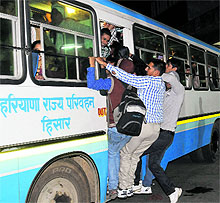 Youths hang on to the door of a Haryana Roadways bus at the Sector 17 ISBT, Chandigarh