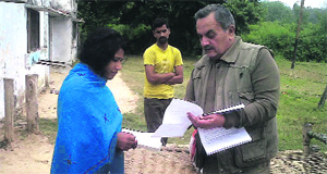 Brijendra Singh, wildlife warden of the Jim Corbett National Park, hands over a cheque to the widow of the deceased forest guard. 