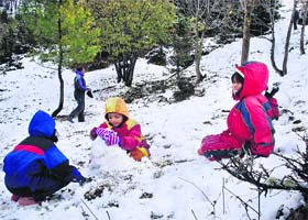Children make a snowman with fresh snow at Gulaba on the Manali-Rohtang highway on Sunday