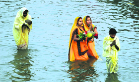 Women perform Chhath puja in a rivulet.