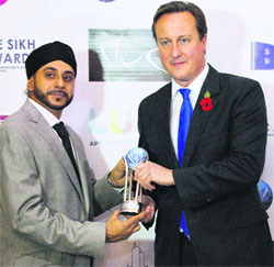British PM David Cameron receives the Sikh Award from Navdeep Singh, the award founder, in London on Friday.