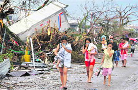 People walk with their noses covered to avoid the stench emanating from the bodies in Tacloban city of Philippines on Sunday.