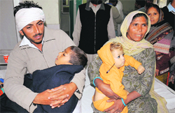 The man and his mother hold the kids who were rescued from drowning in the Rajasthan Feeder near Panjala village in Lambi, at the Civil Hospital in Bathinda on Monday. The mans wife allegedly attempted suicide by jumping into the canal along with the kids. Her body is yet to be traced. Tribune photo: Pawan Sharma