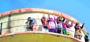 Asha workers who are atop a water tank for the past four days in support of their demands at Vikasnagar, Dehradun, on Monday 