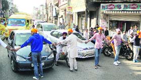 Supporters of the sarpanch of Hirapur village block the traffic by making a human chain at Company Bagh Chowk in Jalandhar on Monday