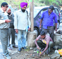 MC staff snap the water connection of a defaulter near the Domoria bridge in Ludhiana on Monday. Photo: Inderjeet Verma