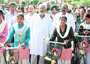 Health Minister Surjit Kumar Jyani and District Education Officer Sandeep Dhuria distribute bicycles among girl students in Fazilka.