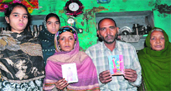 The parents of the missing girls show their photos at their house at Jwalapur, Haridwar, on Tuesday. Tribune photo: Rameshwar Gaur