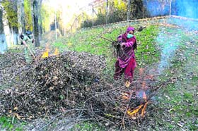 A woman burns leaves to make charcoal in Srinagar on Thursday