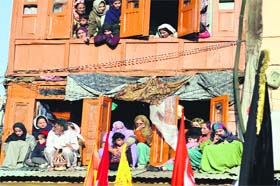 Women look at the devotees take part in self-flagellation in Srinagar on Thursday