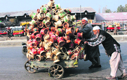 Two elderly push a cart loaded with kangris in Srinagar on Saturday. Tribune photo: Amin War