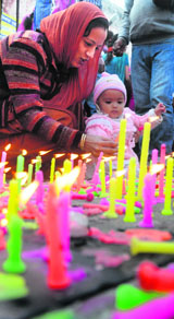 A mother helps her child light a candle on the birth anniversary of Guru Nanak Dev at Gurdwara Dukh Nivaran Sahib in Ludhiana.