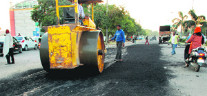 Workers carry out patchwork on the road separating Sectors 5 and 6 in Panchkula on Monday.