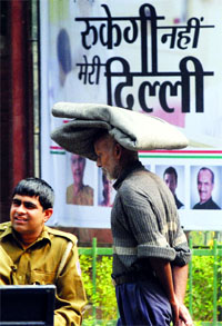 A man walks in front of a campaign poster ahead of the Delhi Vidhan Sabha elections in New Delhi on Wednesday