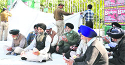Sikh devotees hold a protest by reciting religious hymns in front of Gandhi Park, while policemen remove the tents put up by them in Dehradun on Thursday. Tribune photo: Abhyudaya Kotnala