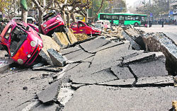 Damaged vehicles lie by a street after an oil pipeline exploded, ripping roads apart, turning cars over in Qingdao City of China on Friday.  AFP