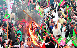 Activists of the Pakistan Tehreek-e-Insaaf and the Jamaat-e-Islami burn a US flag to protest against the drone strikes in Peshawar on Saturday