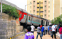 People watch the derailed coaches of the Rajdhani Express that ran onto a nearby road during backing up at the city railway station in Bangalore on Sunday. No one was hurt in the incident
