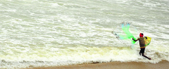 A fisherman casts his net in the Bay of Bengal in Visakhapatnam district on Thursday