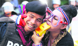 An anti-government protester blows a giant whistle to a riot police officer outside the headquarters of the ruling Pheu Thai Party in Bangkok on Friday.