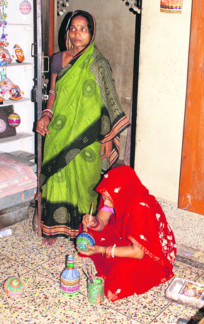 A woman paints in the verandah of her cottage.