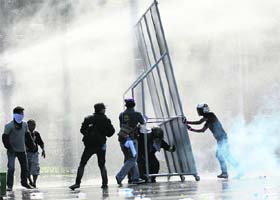 Anti-government protesters use self-made barricade against the water cannons and tear gas fired by the riot police in Bangkok on Sunday