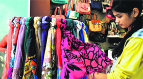A girl looks at a bright coloured stole in Ludhiana.