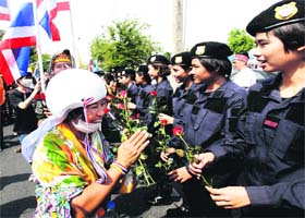 An anti-government protester offers red roses to policewomen at the metropolitan police headquarters in Bangkok on Tuesday