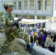 A security man keeps vigil outside a polling booth during the Delhi Assembly elections in East Delhi on Wednesday. 