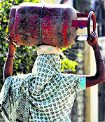 A woman carries an LPG cylinder on the outskirts of Jammu