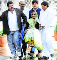 An elderly voter is carried by relatives to a polling station in New Delhi